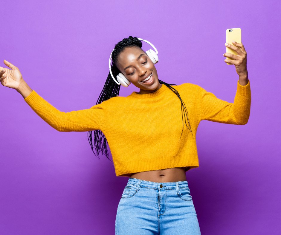 A listener dancing with her phone and headphones against a purple backdrop